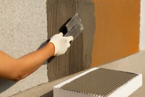 Manopera plasa cu adeziv aplicată pe un perete exterior, cu adeziv întins uniform și plasa din fibră de sticlă înglobată corect.